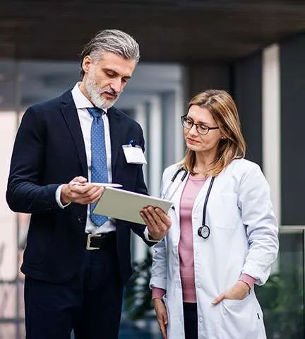 A senior physician and a female doctor reviewing information on a tablet